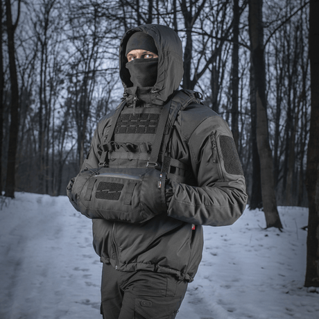 Person iført M-Tac Taktisk Håndvarmer Elite i skov med snebaggrund, holdende hænderne varme i det kolde vejr.