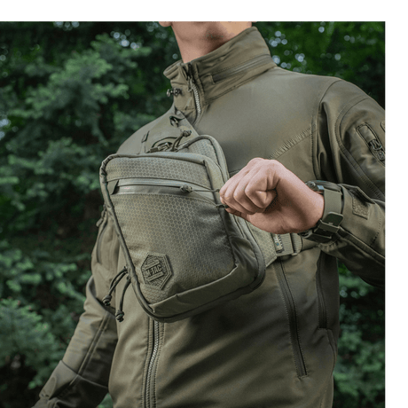 Person med M-Tac Sling pistolveske Elite Hex utendørs i en komfortabel og holdbar veske med justerbar rem og romslige rom.