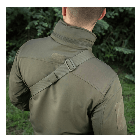 Mann bærer M-Tac Sling pistolveske Elite Hex med justerbar skulderrem i en utendørs setting