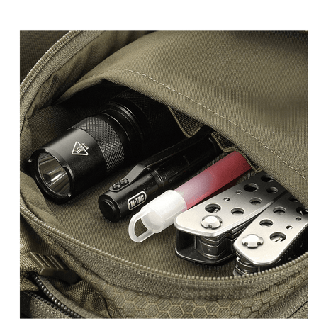Detalj av M-Tac Sling pistolveske Elite Hex med lommelykt, multitool og kulepenn synlige i lommen.