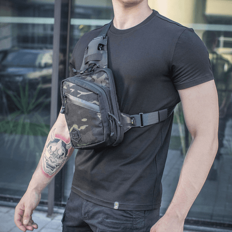 M-Tac Sling pistolveske Elite Hex båret av en mann i svart t-skjorte, viser veskedetaljer og justerbar skulderrem.