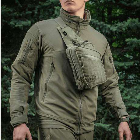 Mann med M-Tac Sling pistolveske Elite Hex, allsidig og stilfull veske for skjult våpen, laget av slitesterkt Cordura 1000D-materiale.