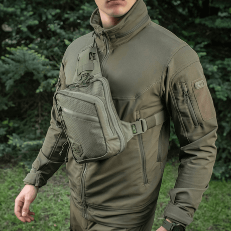 M-Tac Sling pistolveske Elite Hex i Cordura, båres av person med justerbar rem foran skogbakgrunn