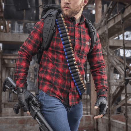 Jeger med M-Tac Bandolier Elite fylt med 12/16 kaliber skudd, klar til jakt i forlatt bygning.