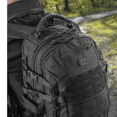 Mann iført M-Tac Mission Pack Elite ryggsekk med ergonomisk design og MOLLE LASER CUT-system i skogmiljø.