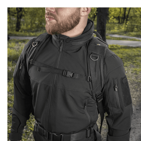 Mann bærer M-Tac Mission Pack Elite-ryggsekk i skogsområde, viser holdbarhet og stilfullt design i Cordura 1000D-stoff.