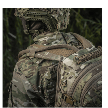 Person iført camouflageuniform og M-Tac Mission Pack Elite med MOLLE LASER CUT i skogmiljø for ergonomisk funksjonalitet.