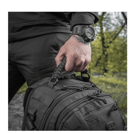 Mann holder M-Tac Mission Pack Elite ryggsekk med MOLLE LASER CUT-system, laget av slitesterkt Cordura 1000D.