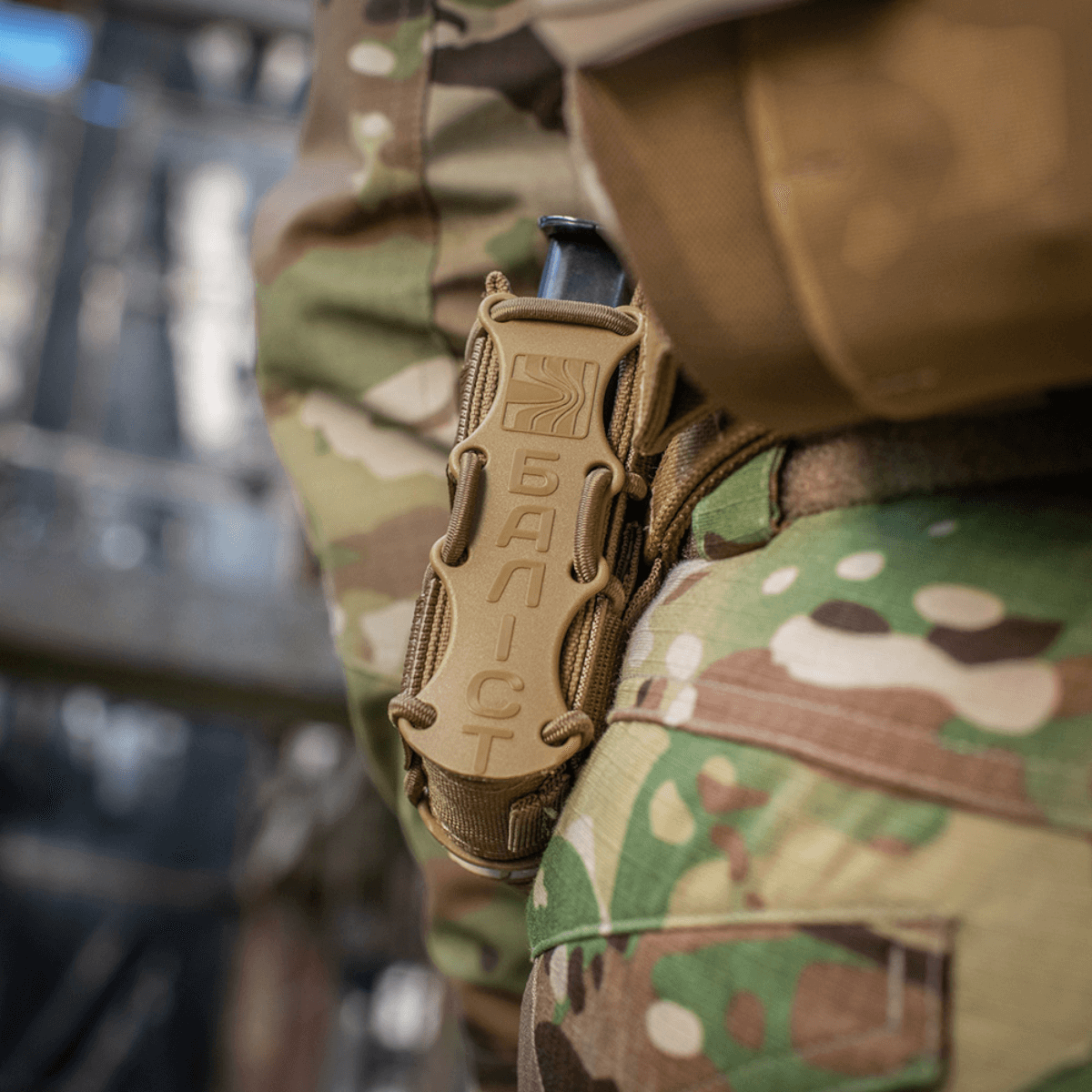 Camouflageklædt person udstyret med M-Tac Pistolmagasinlomme Kolchan monteret på bæltet i udendørsmiljø.