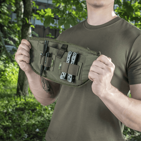 Mann viser M‑Tac belteveske Elite Hex med verktøy, ideell for taktisk og daglig bruk, laget av Cordura med modulære lommer.