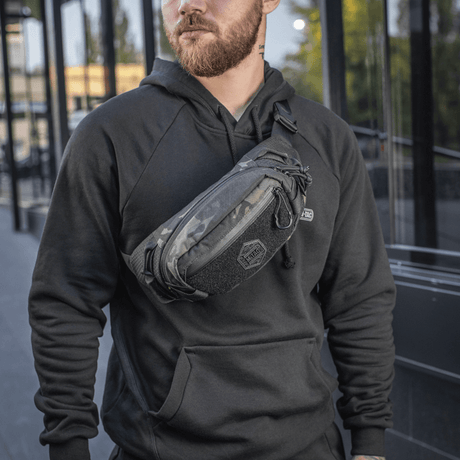 Mann bærer M‑Tac belteveske Elite Hex i urbant miljø, moteriktig og funksjonell med Cordura og YKK-glidelåser, perfekt for hverdagsbruk.