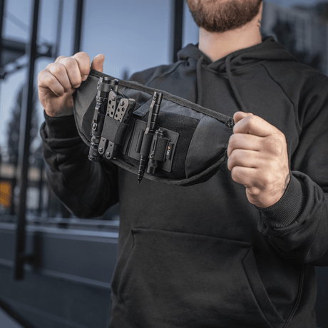 Mann holder M‑Tac belteveske Elite Hex, kompakt og funksjonell med Cordura-stoff og YKK-glidelåser, ideell for taktisk utstyr.