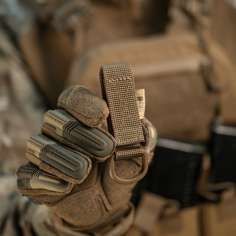 M-Tac feste med D-ring i hansket hånd for MOLLE-tilkobling, ideell for taktisk bruk med sikker Velcro-lukking.