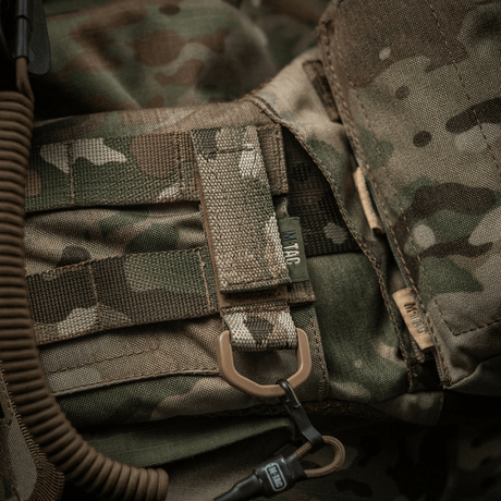 M-Tac feste med D-ring på en kamuflasjevest med MOLLE-system og Velcro-lukking, ideell for taktisk bruk og montering av utstyr.