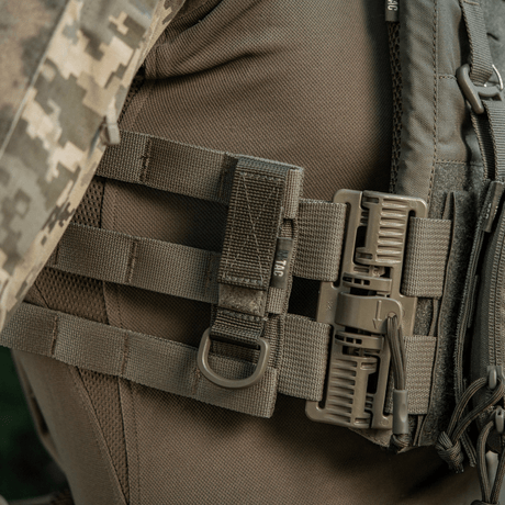 M-Tac feste med D-ring festet på MOLLE-utstyr med Velcro, ideell for taktisk bruk med sikker opphengning og justerbar passform.