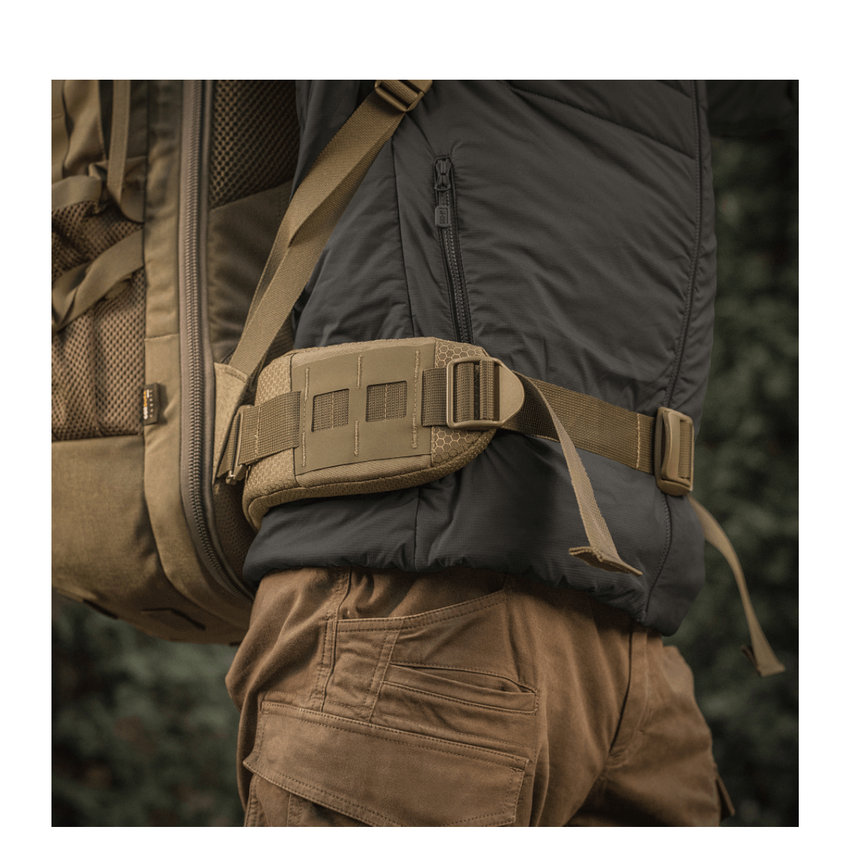 M-Tac Rygsæk Large Elite Hex Gen. IV bæres på ryggen af en person iført udendørstøj, set fra siden i en naturlig omgivelser.