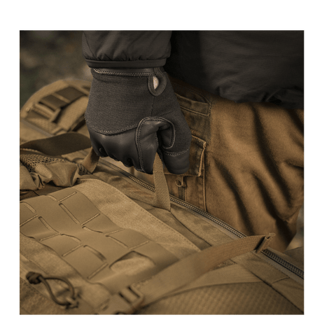 Bruker iført hansker holder M-Tac Ryggsekk Large Elite Hex Gen. IV, laget av slitesterk Cordura 500D og Hex 1000.