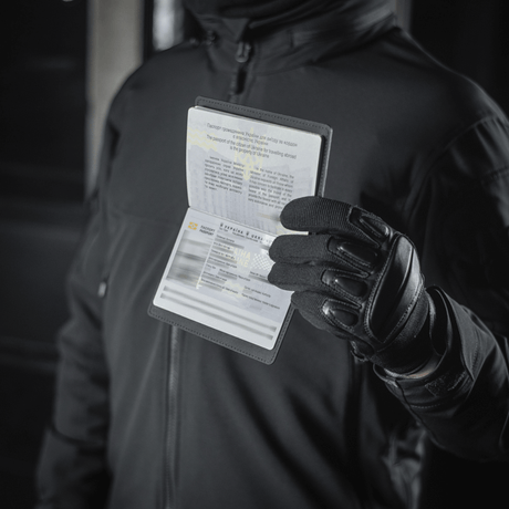 Person med M‑Tac Pascover holder et pass, beskytter mot slitasje og skader, moderne polymer, stilfullt design, ideelt for reiser.