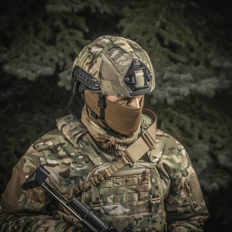 Soldat iført M‑Tac Hjelmcover Shroud Elite i MULTICAM-kamuflasje, designet for TOR-D-hjelmer for effektiv kamuflasje i terrenget.
