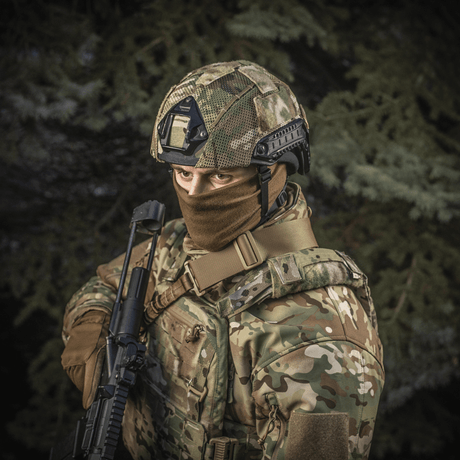 Soldat iført M‑Tac Hjelmcover Shroud Elite i MULTICAM for TOR-D-hjelmer, med våpen i skoglandskap.