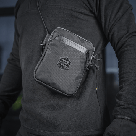 M-Tac Pocket Bag Elite HEX på en person, kompakt veske i slitesterkt materiale med YKK-glidelåser, perfekt for EDC-utstyr.