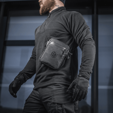 M-Tac Pocket Bag Elite HEX båret av en mann, egnet for kompakt oppbevaring av EDC-utstyr med slitesterkt materiale og YKK-glidelåser.
