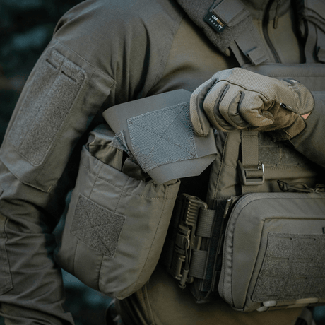 Person i taktisk bekledning holder M‑Tac Medic Pouch Vertical Large Elite, innovativ medisintaske laget av holdbart Cordura 500D-materiale.