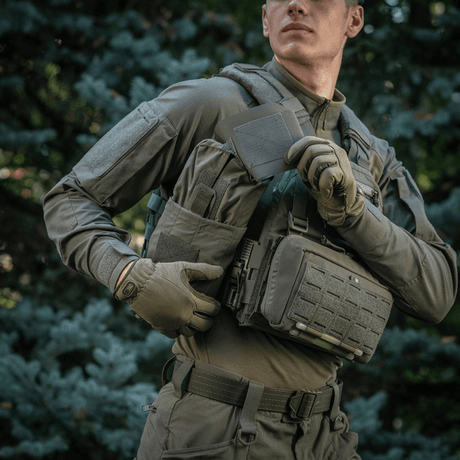 Mann bærer M‑Tac Medic Pouch Vertical Large Elite i felten med natur i bakgrunnen.