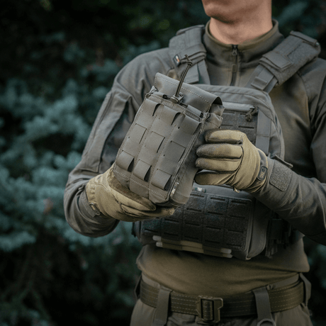 M‑Tac Medic Pouch Vertical Large Elite i bruk, holdt av person i militær bekledning med utsikt over taktisk bakgrunn.