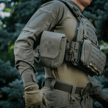 M‑Tac Medic Pouch Vertical Large Elite festet til taktisk vest utendørs, laget av sterkt Cordura 500D-materiale for sikker oppbevaring.