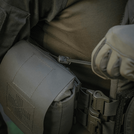 M‑Tac Medic Pouch Vertical Large Elite festet til taktisk utstyr, laget av holdbart Cordura 500D, viser sikker oppbevaring av medisinsk utstyr.