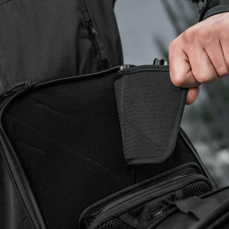 Person demonstrerer skjult våpenrom i M-Tac Tablet Bag Laser Cut Hex med modulære innsatser og hurtig tilgangsdesign.