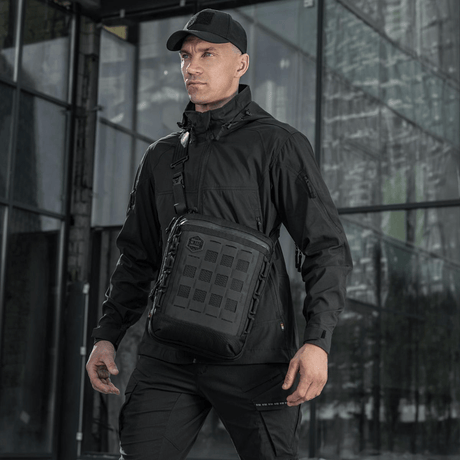 Mann med M-Tac Tablet Bag Laser Cut Hex i svart, ideell for EDC, dokumenter og nettbrett, laget i holdbart Cordura-materiale.