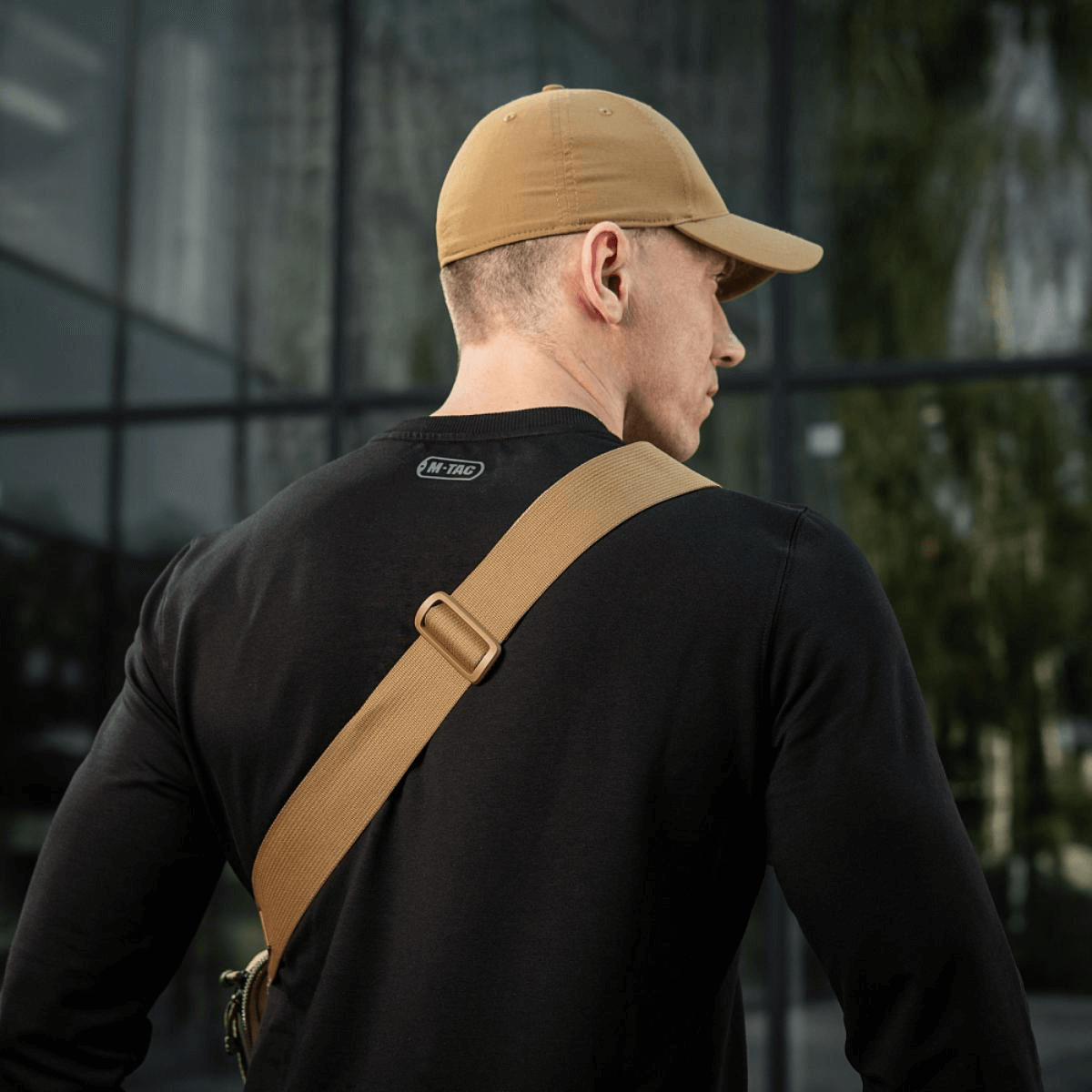 Mand iført kasket med M-Tac Tablet Bag Laser Cut Hex, designet til EDC og hurtig adgang til skjult våben.