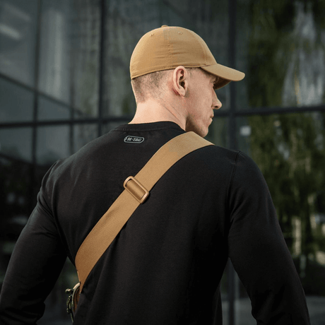 Mann iført svart genser og beige caps sett bakfra med M-Tac Tablet Bag Laser Cut Hex skrått over skulderen.