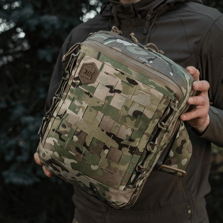 M-Tac Tablet Bag Laser Cut Hex i camouflagedesign holdt i hånden, viser frontpanel med Laser Cut MOLLE-system for ekstrautstyr.