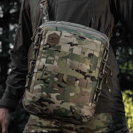 M-Tac Tablet Bag Laser Cut Hex i camouflagedesign med Laser Cut MOLLE og holdbart Cordura-materiale, båret av en person i naturen.