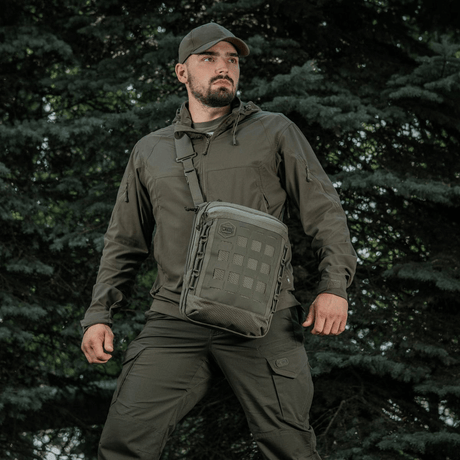 Person med M-Tac Tablet Bag Laser Cut Hex-veske i skogmiljø.