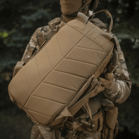 M-Tac STURM Elite ryggsekk holdt av person i taktisk antrekk i naturen, laget av Cordura for holdbarhet.