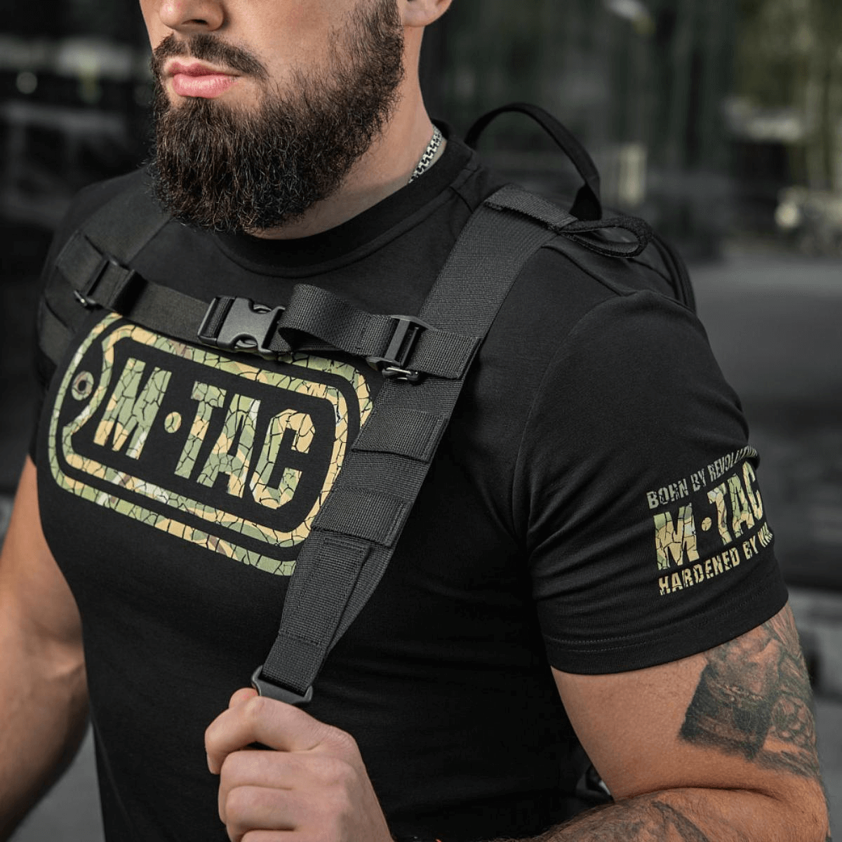 Mand iført M-Tac STURM Elite Rygsæk med taktiske stropper og M-Tac logo på T-shirt, ideel til kortvarige ture.