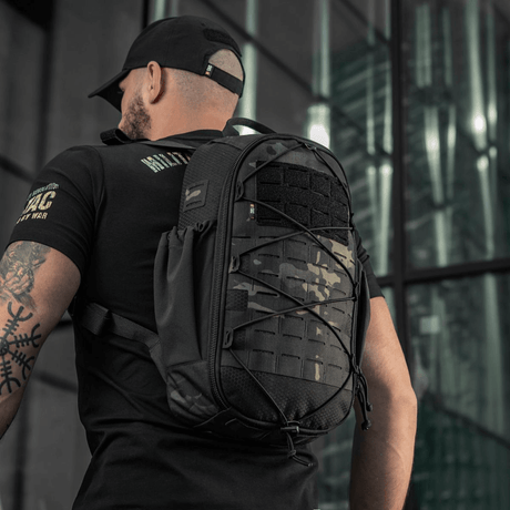 Mann bærer M-Tac STURM Elite ryggsekk med MOLLE Laser Cut-frontpanel i urbant miljø, taktisk og holdbar, for korte opphold i feltet.