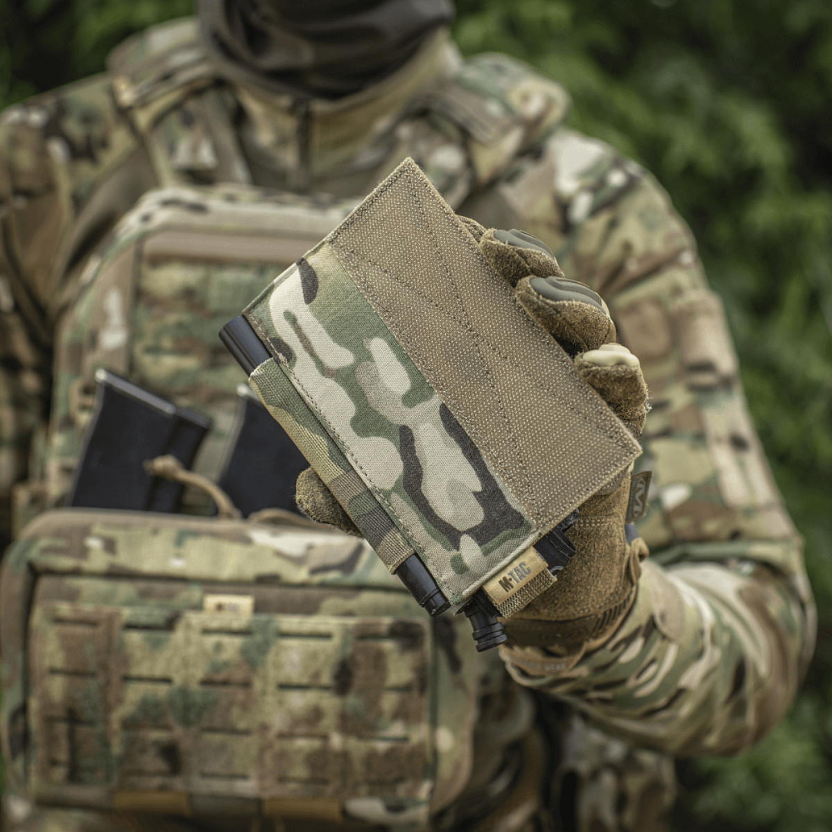 M‑Tac Tourniquet Pouch Elastic Gen.5 holdt af soldat i camouflageuniform, ideel til CAT tourniquet på taktisk udstyr.