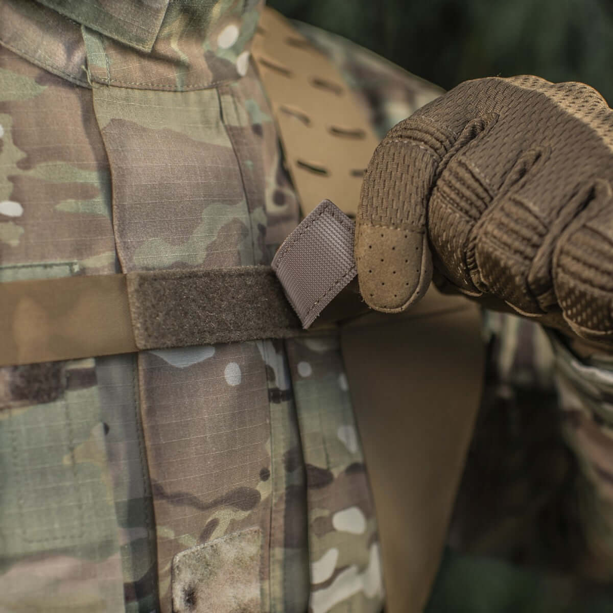 Person, der justerer M-Tac Skulderstropper til taktisk bælte Laser Cut i kamuflagejakke.