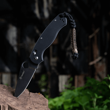 M-Tac Knife Lanyard Scandinavian paracord-tilbehør på lommekniv i naturlige omgivelser for stil og funksjon.