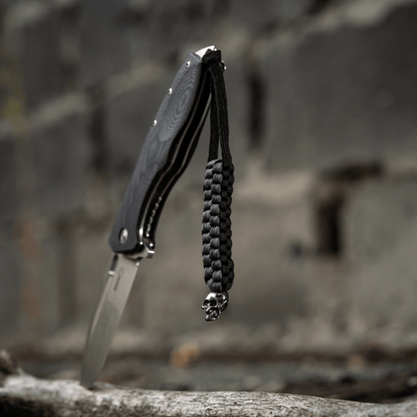 Svart M-Tac Knife Lanyard Cuboid Skull paracord med dekorativ Cuboid Skull-perle, flettet for kniv, unikt uttrykk og praktisk bruk.