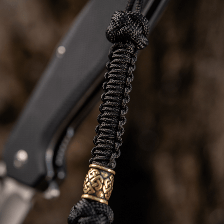 M-Tac Knife Lanyard Celtic i svart flettet paracord med dekorativ detalj, tilfører stil til kniv og gjør den lettere å finne.