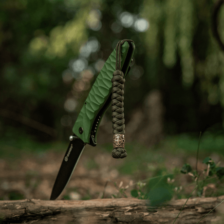 M-Tac Viper Lanyard Scandinavian med flettet paracord og Viper-perle ved en lommekniv i naturen. Stilfullt tilbehør.