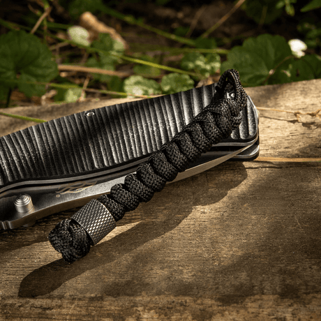 M-Tac Viper Lanyard Stainless Steel med flettet paracord og Viper-perle, stilfullt knivtilbehør, svart lanyard på trebakgrunn.
