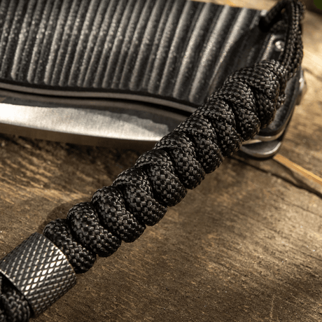 M-Tac Viper Lanyard Stainless Steel med flettet paracord og perle i rustfritt stål, som kompletterer knivens utseende.