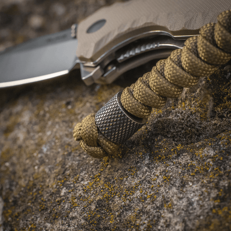 M-Tac Viper Lanyard Stainless Steel med flettet paracord og perle i rustfritt stål på en kniv, stilfullt tilbehør for rask tilgang.